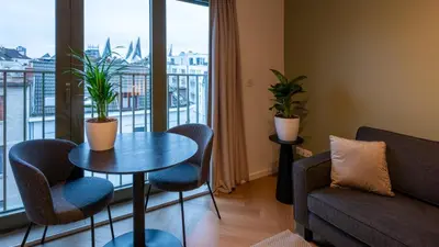 a living room with a table and chairs and a window at Pacific Residences - Studio in Antwerp