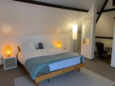 a bedroom with a bed with two lamps and a chair at Appartement séparé avec parking dans villa in Vilvoorde