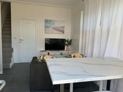 a living room with a white table and a tv at Appartement séparé avec parking dans villa in Vilvoorde