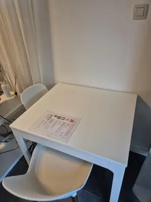a white table with two chairs and a newspaper on it at Appartement séparé avec parking dans villa in Vilvoorde