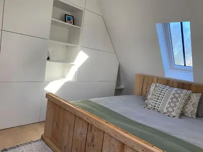 a bedroom with a wooden bed and a window at The Conservatory, a cosy holiday home located central between Gent Antwerpen & Brussel in Lokeren