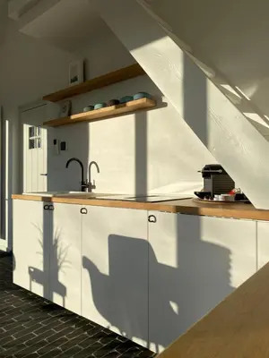 a kitchen with white cabinets and a sink at The Conservatory, a cosy holiday home located central between Gent Antwerpen & Brussel in Lokeren