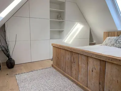 a bedroom with a wooden bed and white walls at The Conservatory, a cosy holiday home located central between Gent Antwerpen & Brussel in Lokeren