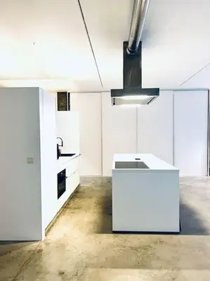 a kitchen with white cabinets and a chandelier at Loft Antwerp - Eilandje in Antwerp