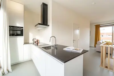 a kitchen with white cabinets and a black counter top at Apartments in Antwerp South in Antwerp