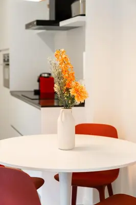 a white table with a vase with orange flowers on it at Apartments in Antwerp South in Antwerp