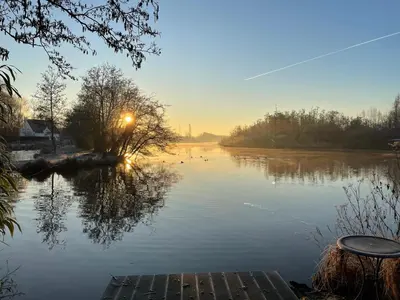 a view of a river with the sun setting in the background at Etablo B&B in Bornem