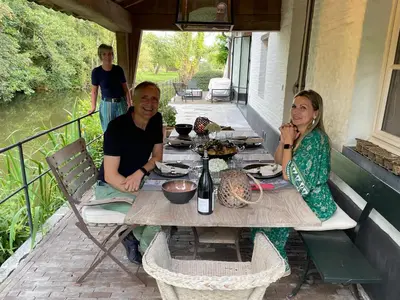 a man and woman sitting at a table on a porch at Etablo B&B in Bornem