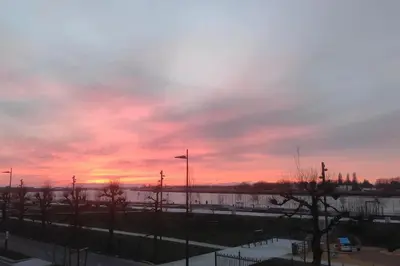 a sunset over a parking lot with trees and a fence at Stunning Riverview apartment in Antwerp