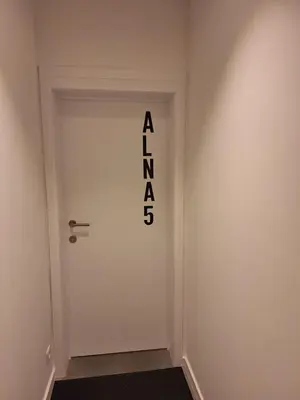 a white door with the alphabet on it at Huis ALNA 5 in Mechelen