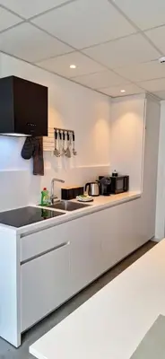 a white kitchen with a sink and a counter at Huis ALNA 5 in Mechelen