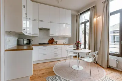 a kitchen with white cabinets and a table and chairs at Charming mansion in vibrant Antwerp in Antwerp