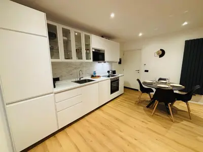 a kitchen with white cabinets and a table and chairs at Cozy Flat in Brussels