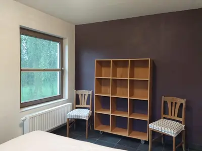 a bedroom with two chairs and a book shelf at Vakantiewoning Nieuwdonk in Berlare