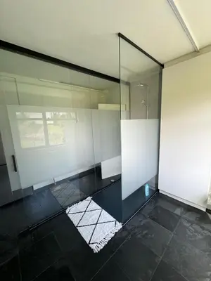 a glass walled bathroom with a shower and a window at Vakantiewoning Nieuwdonk in Berlare