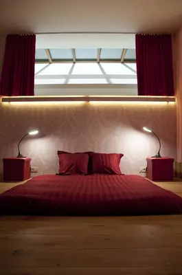 a bedroom with a bed with two lamps and a window at Schopenhauer in Ghent