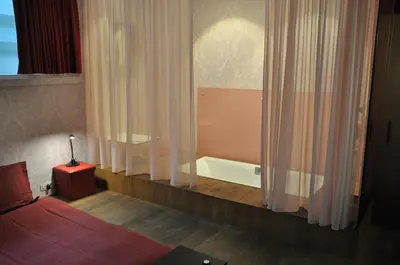 a bedroom with a bed and a bathtub with curtains at Schopenhauer in Ghent