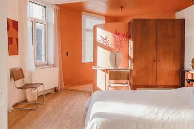 a bedroom with a white bed and a cabinet and windows at Your colourful Antwerp Oasis in Antwerp