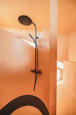 a shower in a bathroom with an orange wall at Your colourful Antwerp Oasis in Antwerp