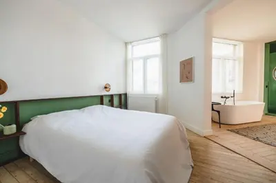a bedroom with a white bed and a bath tub at Your colourful Antwerp Oasis in Antwerp