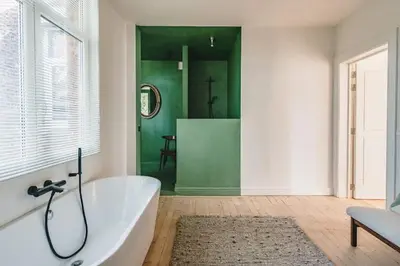 a bathroom with a tub and a green wall at Your colourful Antwerp Oasis in Antwerp