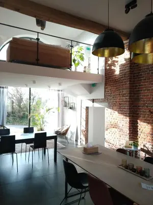 a dining room with a table and chairs and a brick wall at Vakantiewoning De Woestijn - De Schuur in Roosdaal