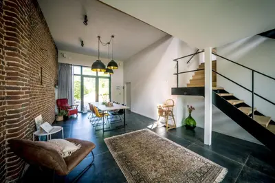 a living room with a staircase and a brick wall at Vakantiewoning De Woestijn - De Schuur in Roosdaal
