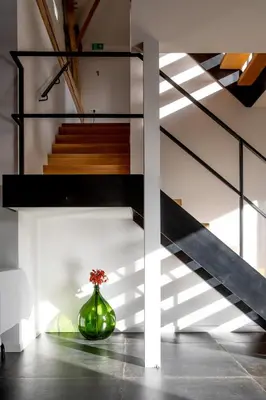 a green vase with flowers in a room with stairs at Vakantiewoning De Woestijn - De Schuur in Roosdaal