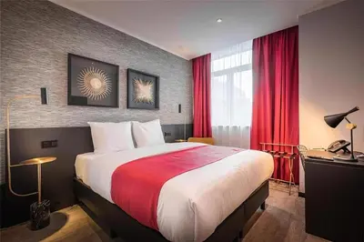 a hotel room with a large bed with red curtains at Hotel Jamingo in Antwerp