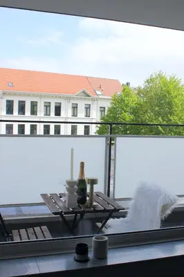 a table on a balcony with a view of a building at Sunny Apartment - Zuid Retreat 1BR Apartment near Scheldt River in Antwerp