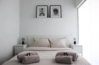 a white bedroom with a bed with two towels on it at Sunny Apartment - Zuid Retreat 1BR Apartment near Scheldt River in Antwerp