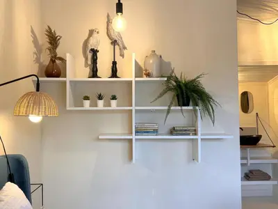 a white shelf on a wall with plants on it at Charlies Chalet in Geel
