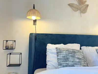 a bed with a blue head board and a lamp at Charlies Chalet in Geel
