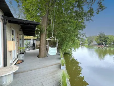 a porch with a swing hanging over a river at Charlies Chalet in Geel