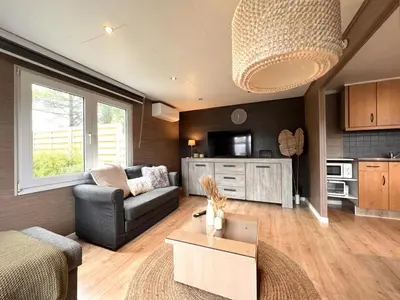 a living room with a couch and a table at Fonnies Chalet in Geel