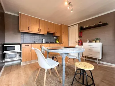 a kitchen with a table and some white chairs at Fonnies Chalet in Geel