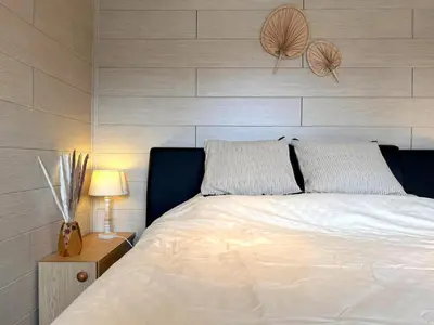 a bedroom with a white bed with a wooden wall at Fonnies Chalet in Geel