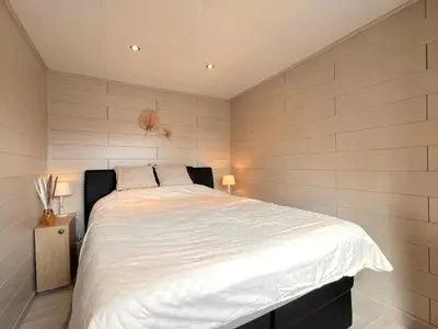 a bedroom with a large bed with white sheets at Fonnies Chalet in Geel