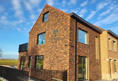 a brick house with a black fence at Trionfo in Gaasbeek
