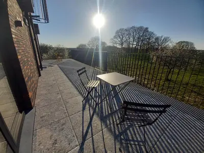 two chairs and a table on a patio with the sun at Trionfo in Gaasbeek