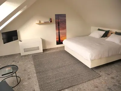 a bedroom with a white bed and a tv at Trionfo in Gaasbeek