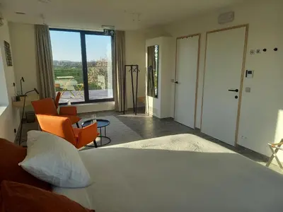 a bedroom with a bed and chairs and a large window at Trionfo in Gaasbeek