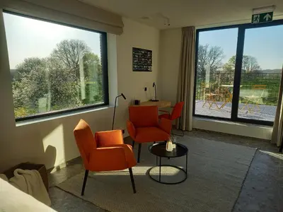 a room with orange chairs and a table and windows at Trionfo in Gaasbeek