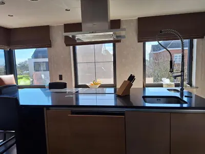 a kitchen with a black counter top and some windows at Kapstertje in Grimbergen