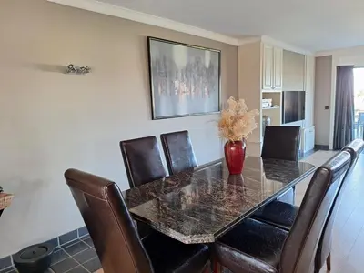 a dining room table with leather chairs and a vase on it at Kapstertje in Grimbergen