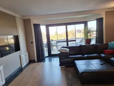 a living room with a leather couch and a table at Kapstertje in Grimbergen