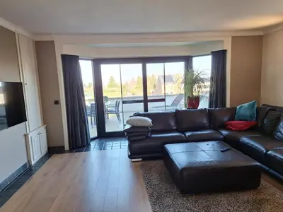 a living room with a leather couch and a table at Kapstertje in Grimbergen