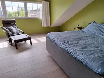 a bedroom with a bed and a chair and windows at Kapstertje in Grimbergen