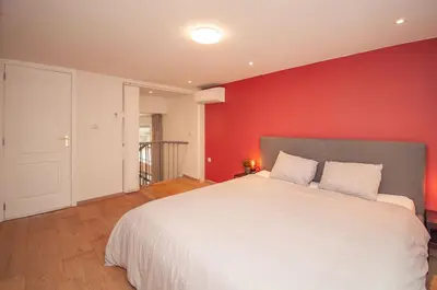a bedroom with a white bed with a red wall at Loft in Antwerp City Centre in Antwerp