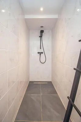 a shower in a bathroom with white tiles at Loft in Antwerp City Centre in Antwerp